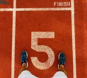 Person som står på löparbana vid nummer 5 och mållinjen – redo för nästa steg