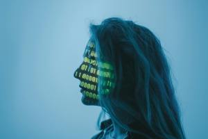 Profilbild av en person med projicerad binär kod över ansiktet, som symboliserar dataskydd, anonymisering och digital informationshantering.