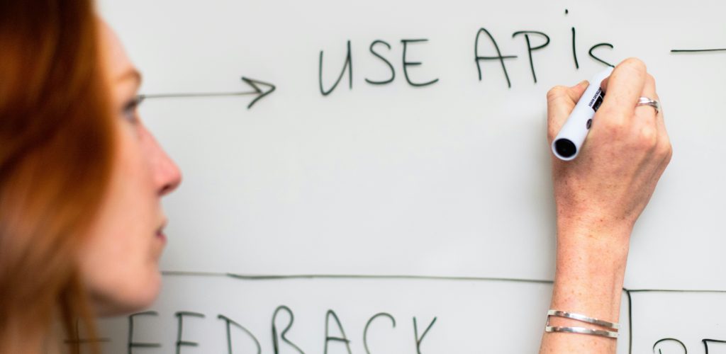 Person skriver ”Use APIs” på en whiteboard som illustrerar integration och API-baserad testdatahantering